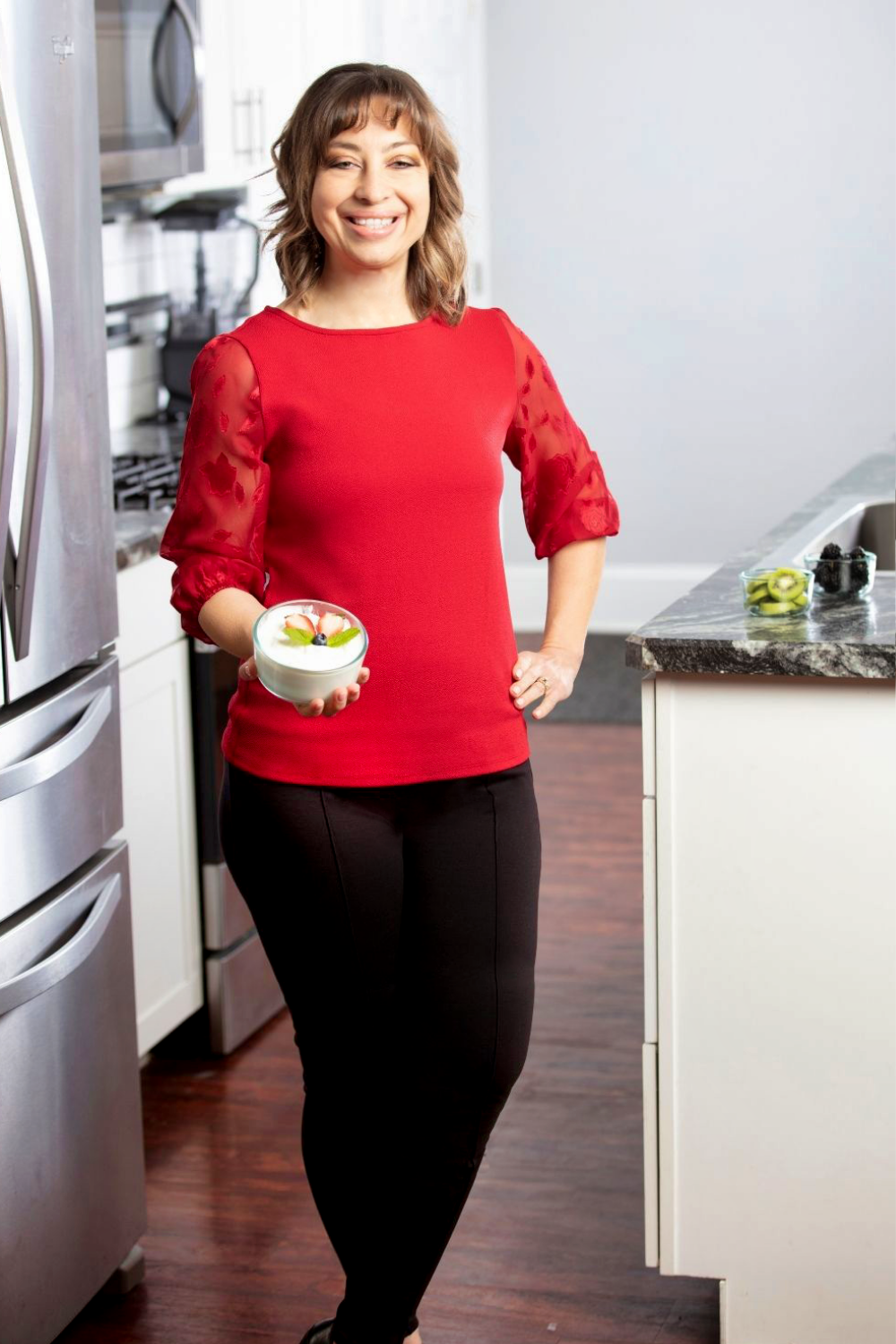 Sara with bowl of yogurt standing in kitchen